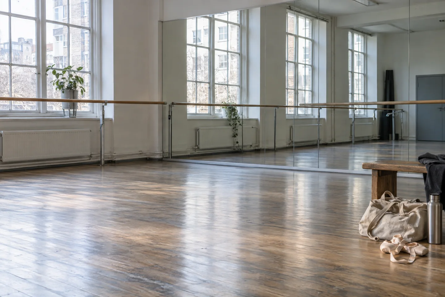 Dansstudio met houten vloer, spiegels en een balletbarre.